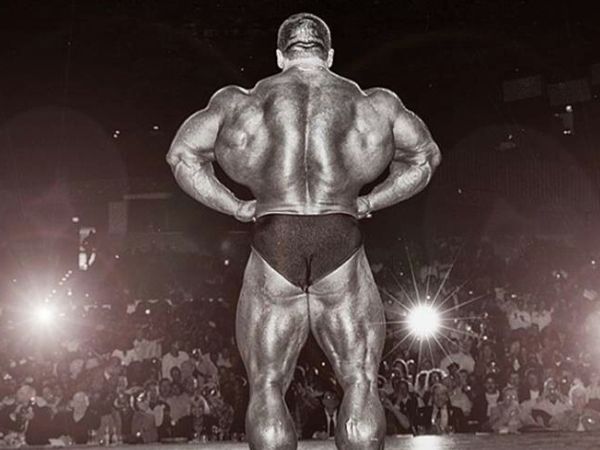 Atleta Dorian Yates, 6 vezes Mr. Olympia, realizando pose de expansão de dorsais no palco de um campeonato de fisiculturismo