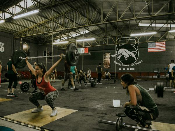 mulher realizando levantamento de peso olímpico em um box de crossfit