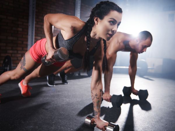 um homem e uma mulher treinando crossfit, fazendo flexões de braços