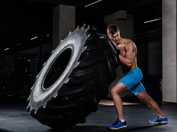 homem se exercitando levantando pneu de caminhão em um box de crossfit