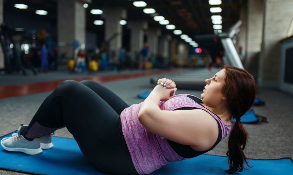 mulher realizando exercício abdominal na academia