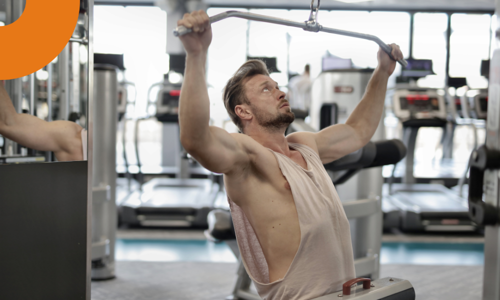 homem realizando uma puxada no pulley em uma academia