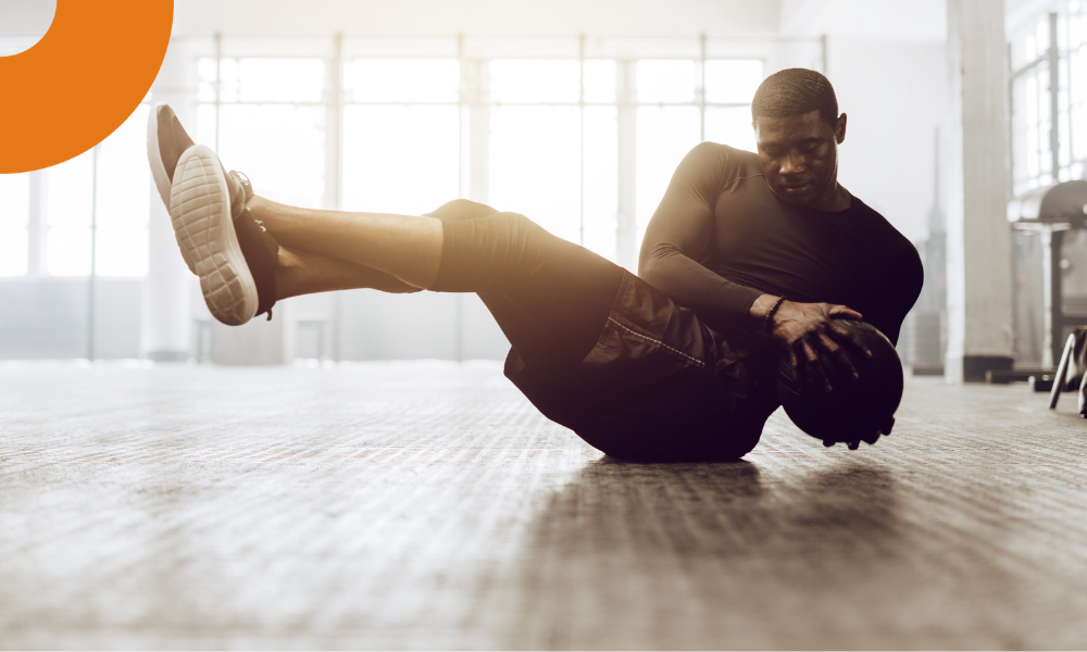 homem fazendo abdominal na academia, utilizando uma medicine ball